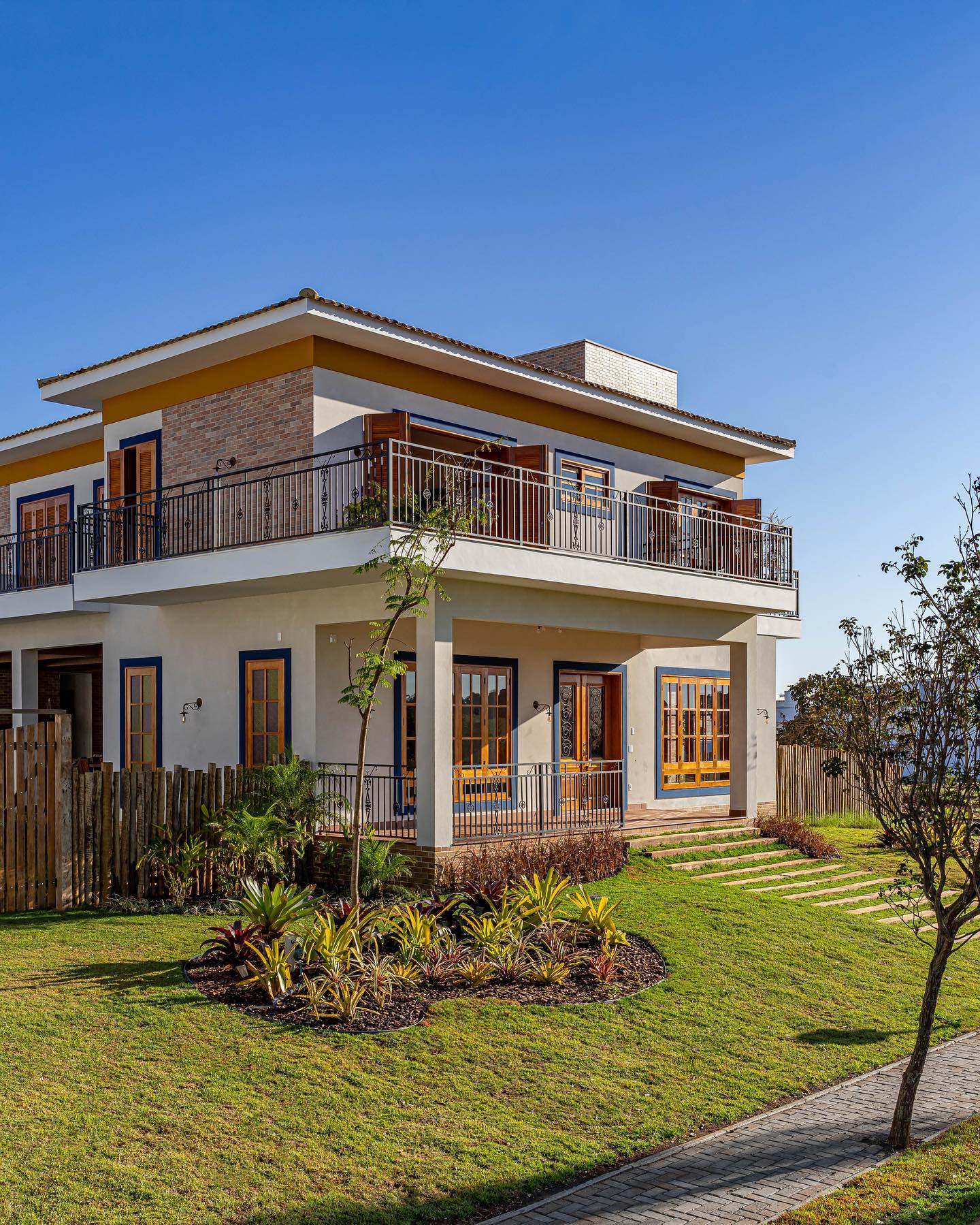 Sobrado colonial contemporâneo com varanda de pilares, esquadrias de madeira e guarda-corpo de ferro